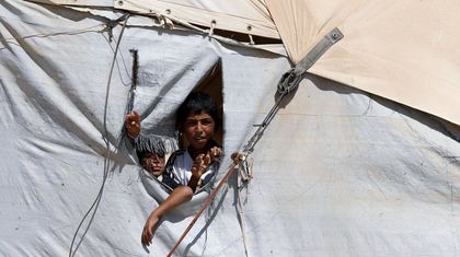 Ni&ntilde;os sirios asoman sus cabezas  por el hueco de una tienda en el campo de refugiados de Al Zaatari, que las Naciones Unidas establecieron en la ciudad jordana fronteriza de Mafraq