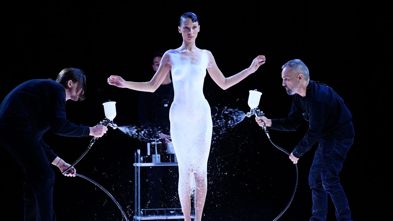 La modelo Bella Hadid siendo rociada con la solución de fibras para crear el vestido final por los creativos de Coperni; Sébastien Meyer y Arnaud Vaillant
